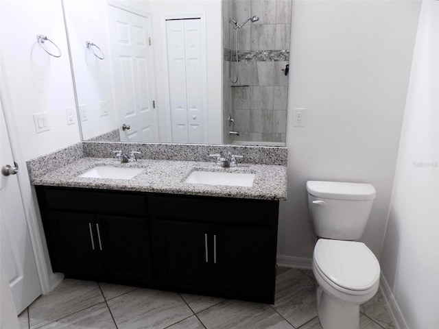 bathroom featuring toilet, tile patterned floors, tiled shower, and vanity