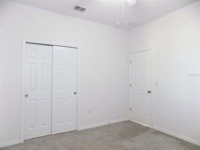 unfurnished bedroom with ceiling fan, light colored carpet, and a closet