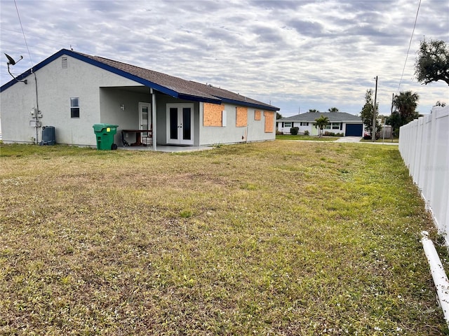 rear view of property with french doors and a yard