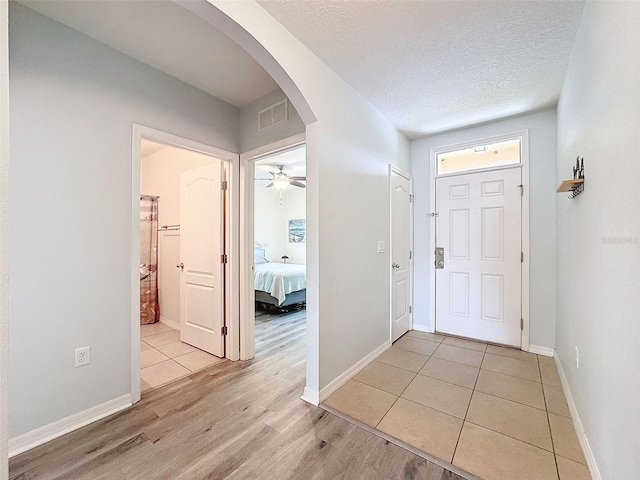 foyer with light wood-type flooring, ceiling fan, and a textured ceiling