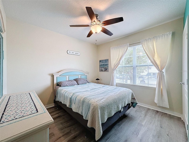 bedroom with a textured ceiling, ceiling fan, and dark hardwood / wood-style floors