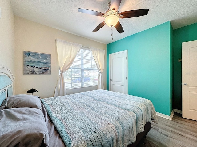 bedroom with a textured ceiling, ceiling fan, and hardwood / wood-style flooring