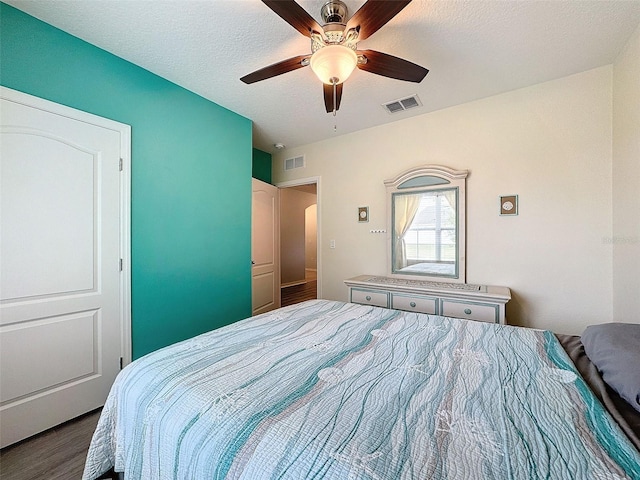 bedroom featuring ceiling fan, a textured ceiling, and dark hardwood / wood-style floors