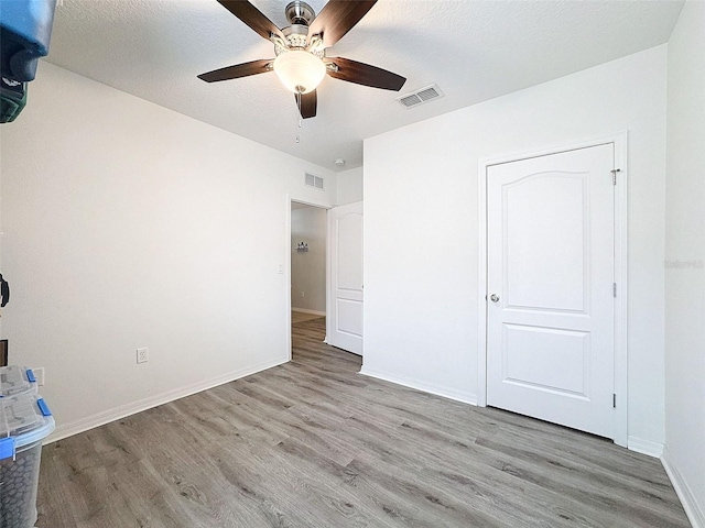 unfurnished bedroom featuring a textured ceiling, ceiling fan, and light hardwood / wood-style flooring