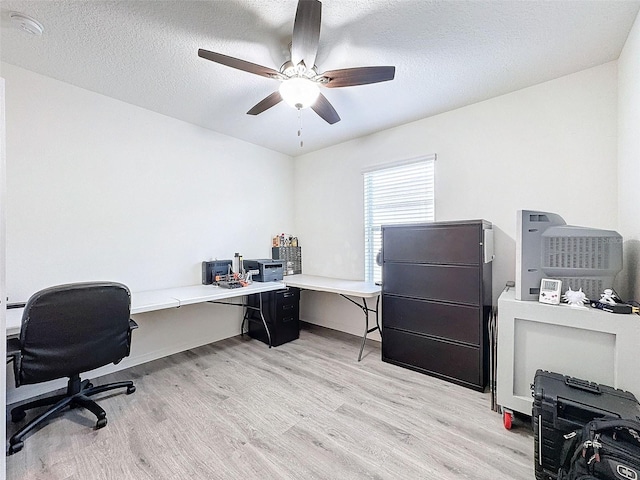 office featuring a textured ceiling, ceiling fan, and light wood-type flooring