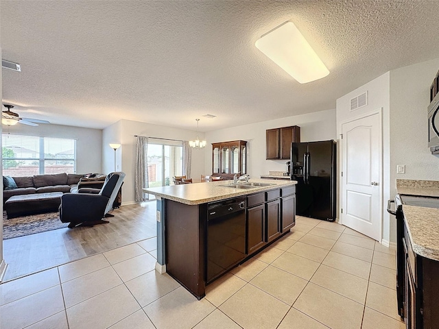 kitchen with a kitchen island with sink, light tile patterned flooring, black appliances, and plenty of natural light