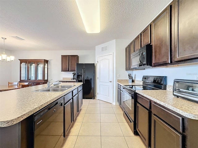 kitchen featuring an inviting chandelier, light tile patterned floors, pendant lighting, an island with sink, and black appliances