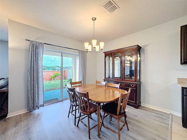 dining space with an inviting chandelier, a textured ceiling, and light hardwood / wood-style flooring