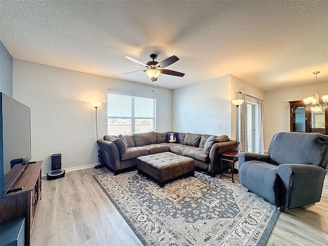 living room featuring ceiling fan with notable chandelier, hardwood / wood-style flooring, and a textured ceiling