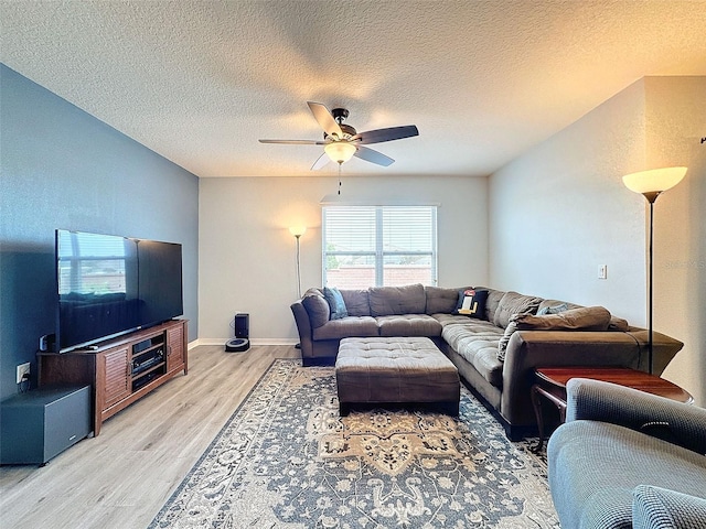 living room with a textured ceiling, ceiling fan, and light hardwood / wood-style flooring