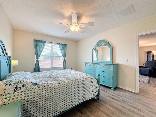 bedroom featuring ceiling fan, light hardwood / wood-style flooring, and a textured ceiling