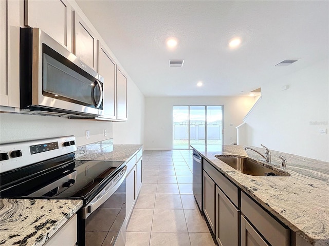 kitchen with light stone counters, sink, appliances with stainless steel finishes, and light tile patterned flooring