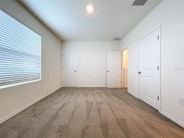 unfurnished bedroom featuring light carpet and a textured ceiling