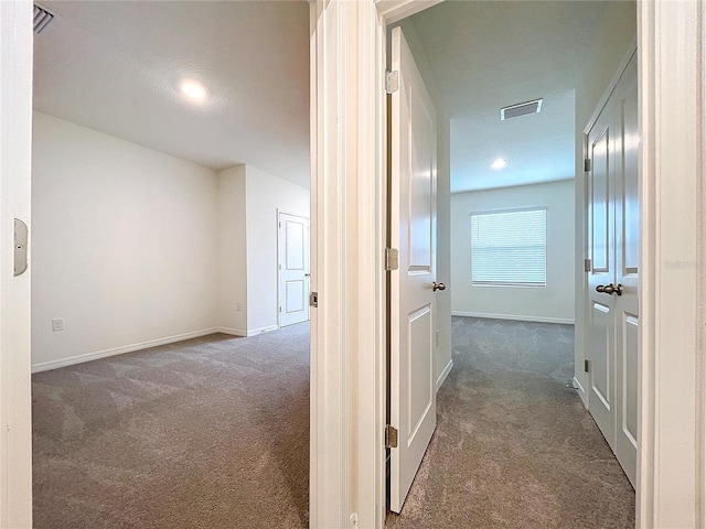 hall featuring dark carpet and a textured ceiling