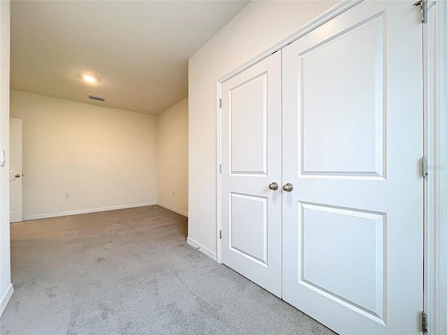 unfurnished bedroom with a closet and light colored carpet