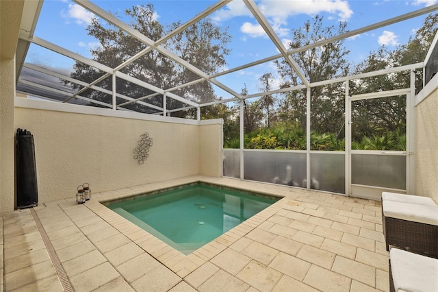 view of swimming pool featuring a patio, glass enclosure, and a jacuzzi