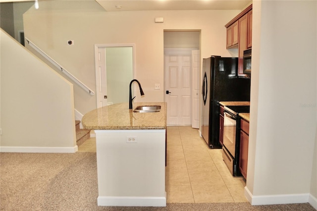 kitchen featuring light colored carpet, black appliances, sink, a kitchen island with sink, and light stone counters