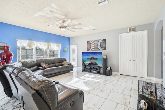 living room with ceiling fan and a textured ceiling