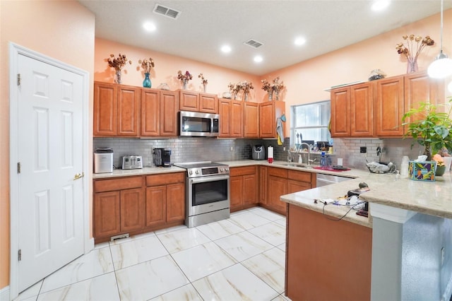 kitchen with decorative light fixtures, appliances with stainless steel finishes, kitchen peninsula, and tasteful backsplash