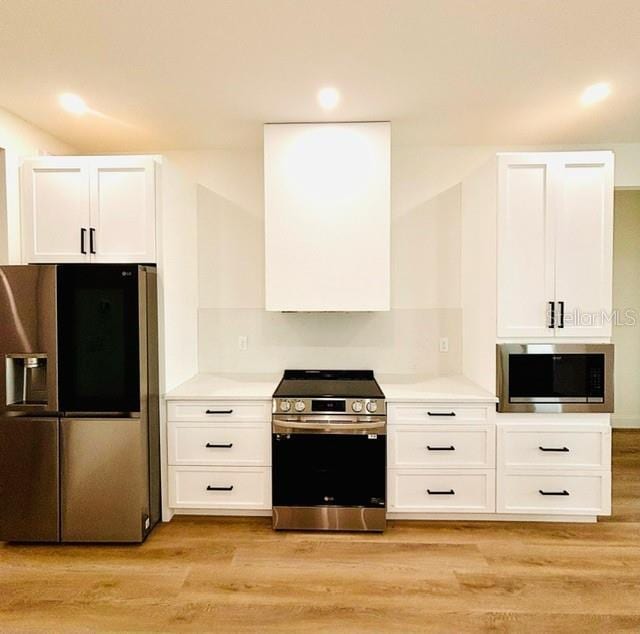 kitchen featuring white cabinets, stainless steel appliances, light hardwood / wood-style flooring, and extractor fan