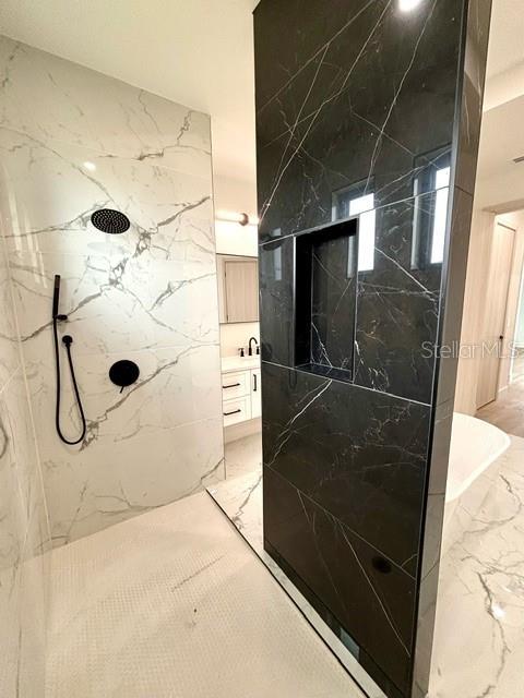 bathroom featuring a tile shower and vanity