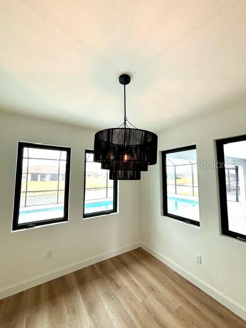 unfurnished dining area featuring hardwood / wood-style flooring, an inviting chandelier, and a wealth of natural light