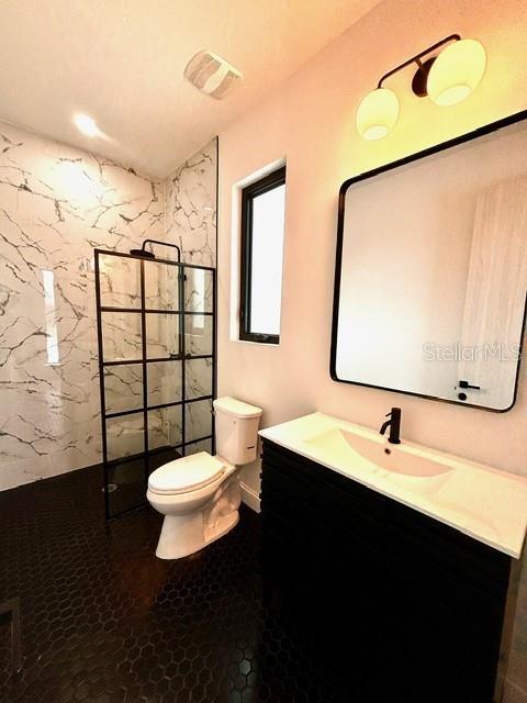 bathroom featuring toilet, walk in shower, and vanity