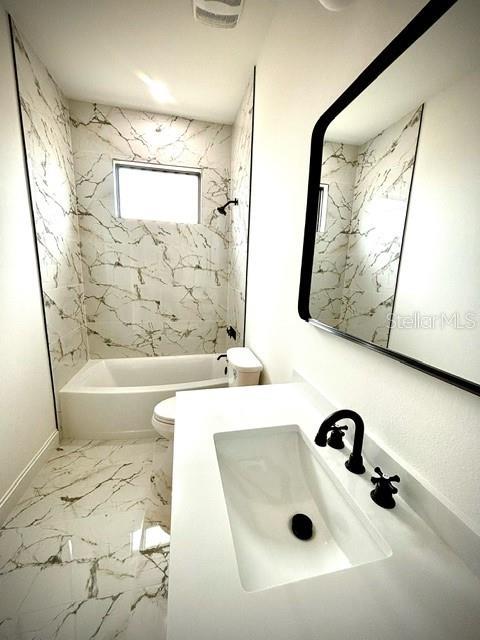 full bathroom featuring tiled shower / bath, vanity, and toilet