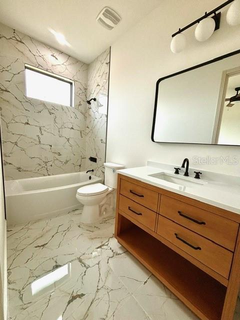 full bathroom with toilet, vanity, and tiled shower / bath