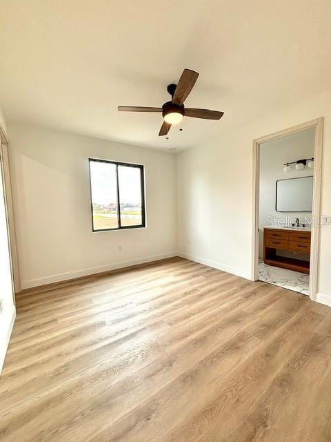 unfurnished bedroom featuring ensuite bathroom, light wood-type flooring, and ceiling fan