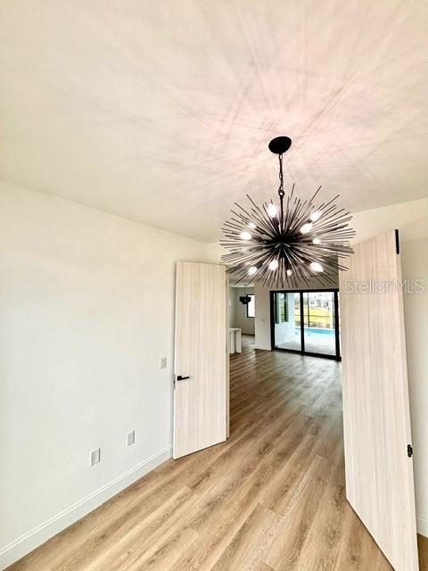 unfurnished room with wood-type flooring and a chandelier