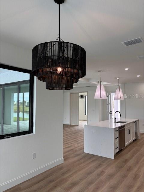 kitchen with dishwasher, decorative light fixtures, a center island with sink, white cabinetry, and sink