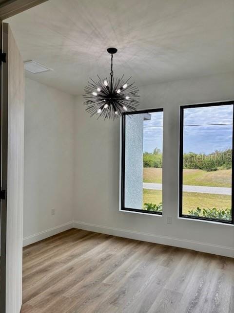 spare room featuring light hardwood / wood-style flooring and a chandelier