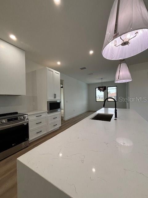 kitchen featuring appliances with stainless steel finishes, white cabinets, light stone counters, and sink