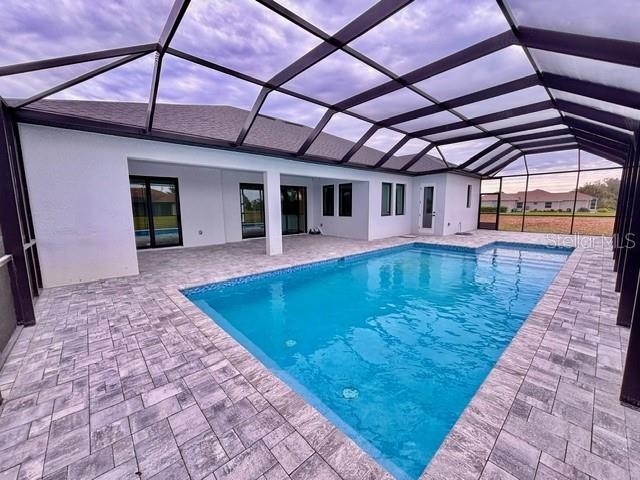 view of swimming pool with glass enclosure and a patio