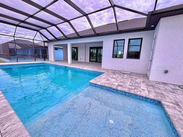 view of pool with glass enclosure and a patio