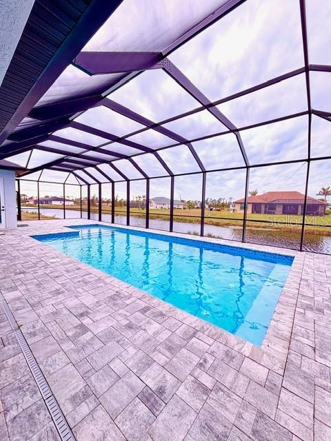 view of pool with a lanai, a patio, and a water view