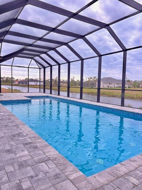 view of swimming pool featuring a patio area, glass enclosure, and a water view