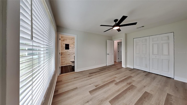 unfurnished bedroom with ceiling fan, light wood-type flooring, ensuite bathroom, and a closet