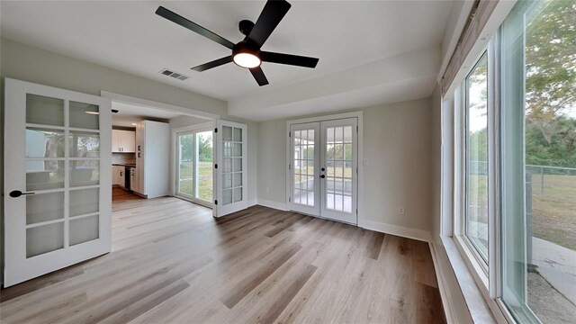 empty room featuring ceiling fan, french doors, and light hardwood / wood-style flooring