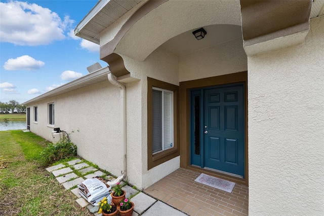 doorway to property featuring a water view and a lawn