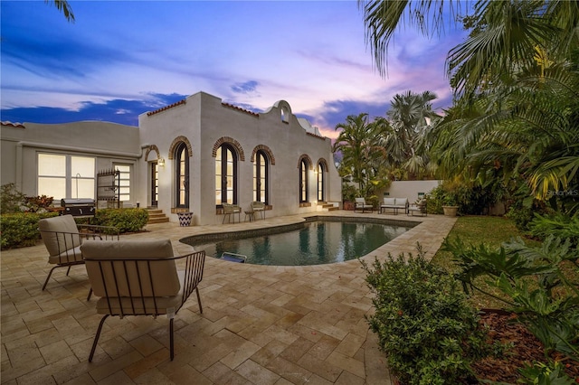 pool at dusk featuring a patio area