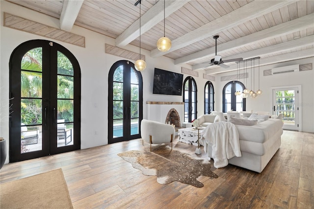 living room featuring hardwood / wood-style flooring, french doors, beam ceiling, ceiling fan, and a wall mounted air conditioner