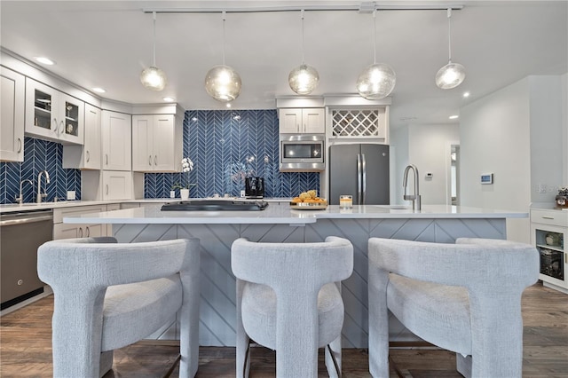 kitchen featuring appliances with stainless steel finishes, pendant lighting, a breakfast bar area, and decorative backsplash