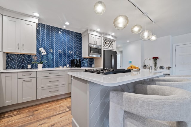 kitchen with a center island with sink, appliances with stainless steel finishes, a breakfast bar area, and decorative backsplash