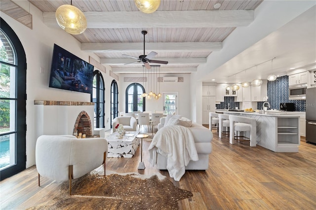 living room featuring ceiling fan, light hardwood / wood-style flooring, a wall mounted air conditioner, and beam ceiling