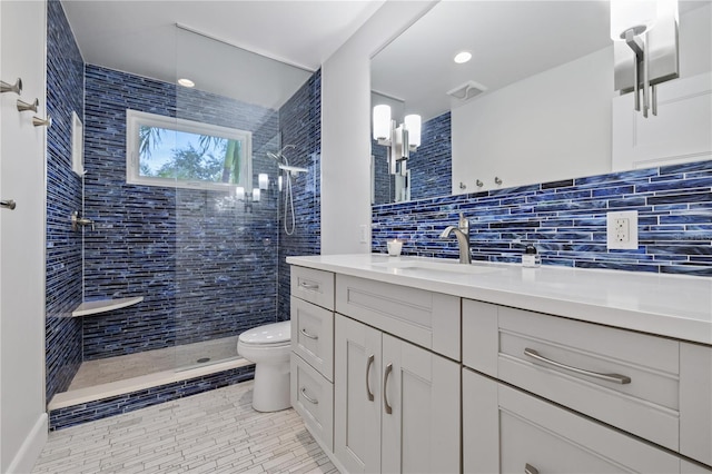 bathroom featuring toilet, vanity, tile walls, a tile shower, and backsplash