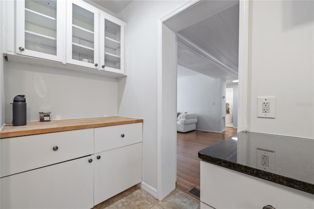 kitchen featuring white cabinetry, light wood-type flooring, and dark stone counters