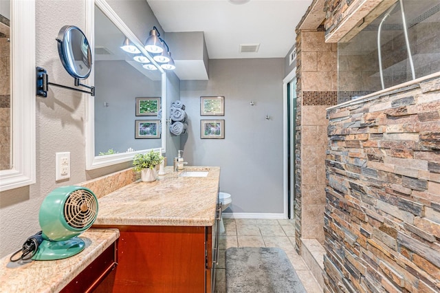 bathroom with toilet, a tile shower, tile patterned floors, and vanity