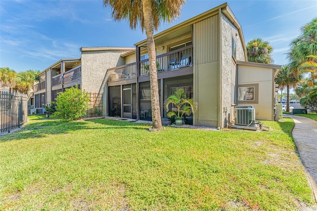 back of property with central AC and a lawn